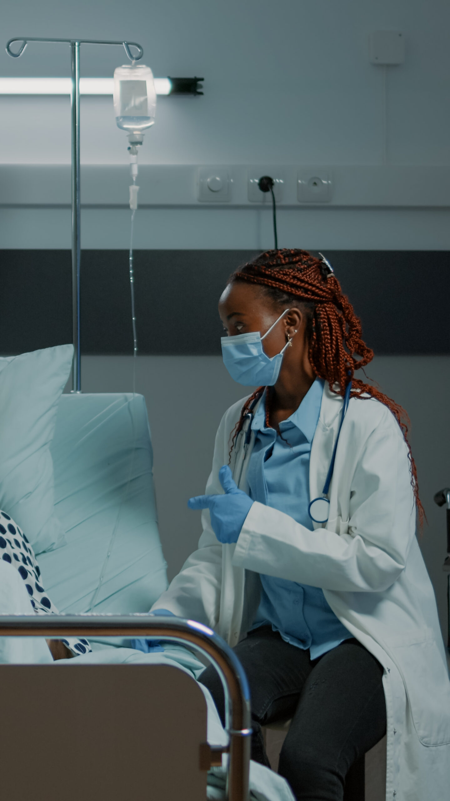 African american doctor talking to sick patient in hospital ward about medical procedures, modern equipment and treatment to heal disease. Old man getting medicine from IV drip bag